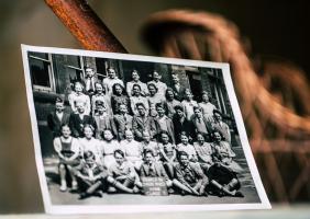 black and white photo of children in rows propped up against a wall